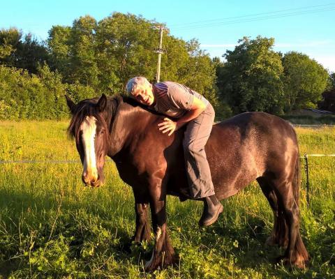 man hugging horse while riding